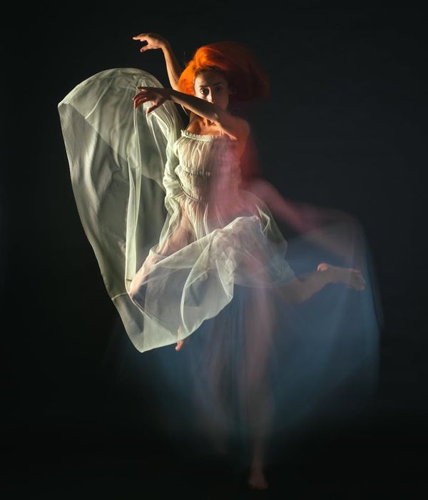 Woman performing a fluid cardio movement in a modern dark studio.